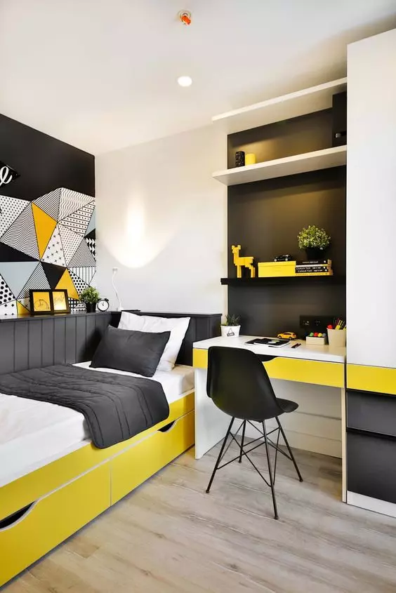 a small and brigth teen room with a built in desk and shelves a bold yellow bed with black and white bedding and bold art on the wall