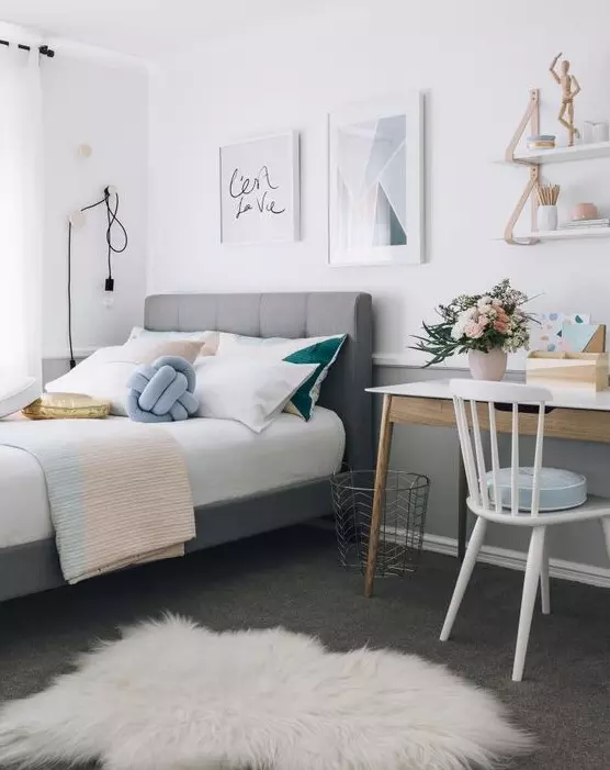 a stylish modern teen bedroom with a grey upholstered bed pastel and color block bedding a desk and a chair some shelves and cool art