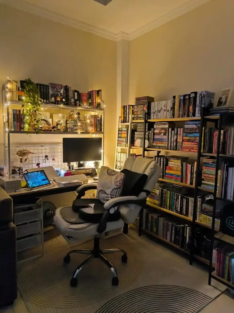 Cozy small bedroom reading nook with tall black bookshelves filled with books, a compact desk setup, warm fairy lights, and a cushioned office chair creating a stylish and clutter-free workspace.
