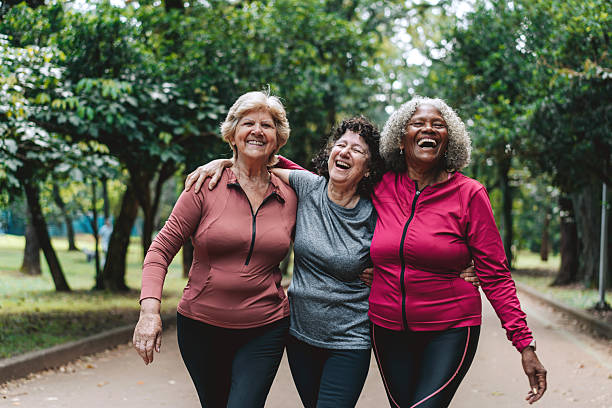 Three older women walking outdoors together, laughing and enjoying an active day with friends.