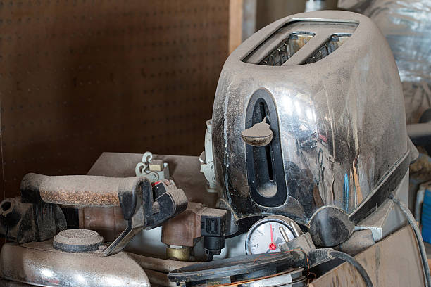 Dusty, worn kitchen appliances and tools piled together, including an old chrome toaster and pressure gauge.