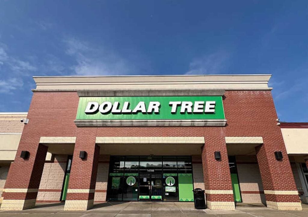Dollar Tree storefront with a large green-and-white sign above the entrance on a red brick building.