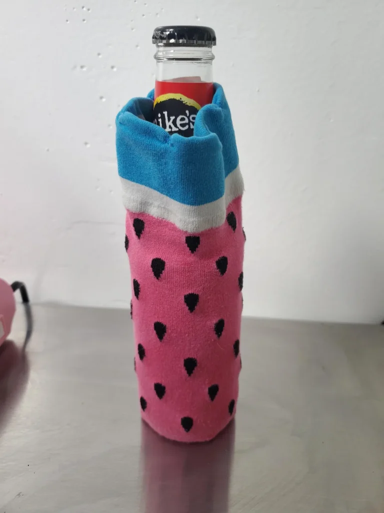 Glass bottle tucked inside a colorful watermelon-patterned sock to provide cushioning during packing.