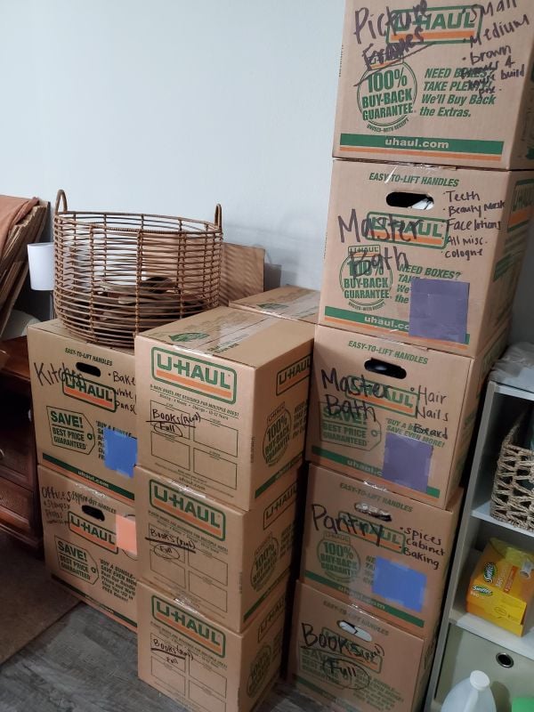 Stacks of labeled U-Haul moving boxes organized by room and contents, with colored tape used for easy identification.
