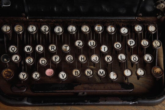 Close-up of a worn vintage typewriter with round keys and a QWERTZ keyboard layout.