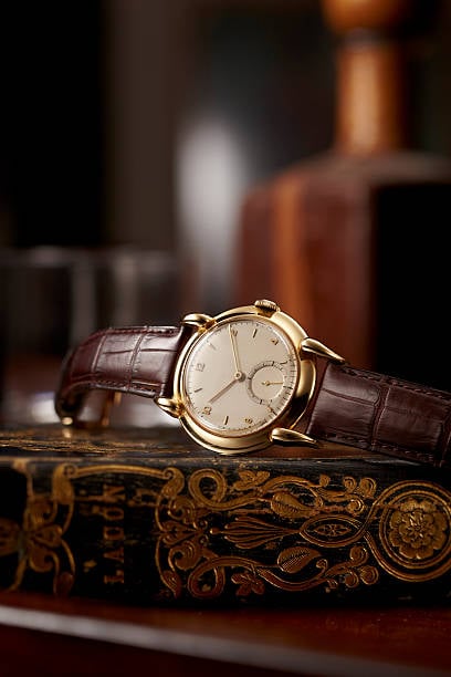 An antique gold watch on a gold leaf book