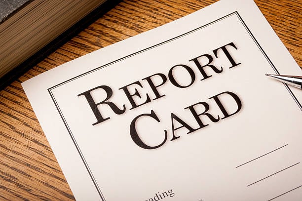 Close-up of a Report Card on a desktop with a mechanical pencil and text book.