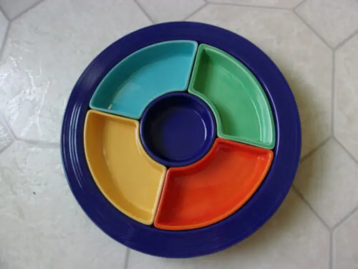 Vintage round divided serving tray with four colorful compartments in turquoise, green, yellow, and orange, surrounding a dark blue center bowl.